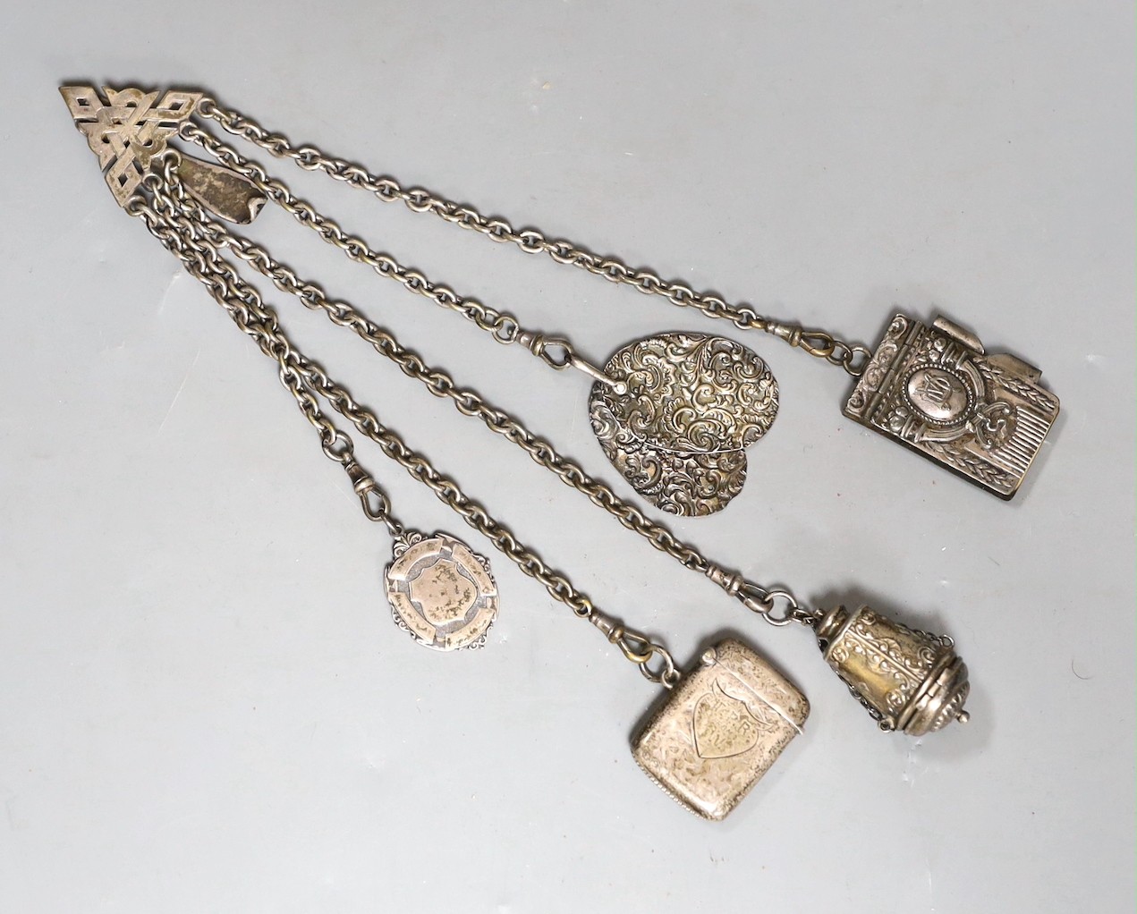 A 19th century plated five chain chatelaine, with a thimble holder, a silver Vesta and a medallion, a note book and two oval metal panels